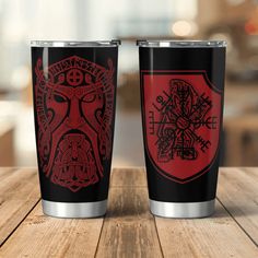 two black and red tumblers sitting on top of a wooden table next to each other