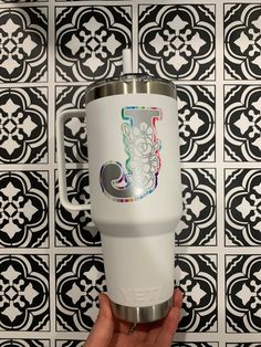 a hand holding a white tumbler cup with the letter j on it