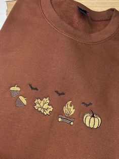 handdrawn fall Halloween crewneck acorns leaves bonfires and pumpkins the best time of year autumn soft style cocoa crewneck 3 color embroidery drawn and designed by me embroidered by me This item is one printed crewneck. Reverse side is blank For non commercial use. Designed, printed and handmade by me. Shipping Processing time 1-2 weeks Due to item being made to order. Usps shipping Due to different monitor calibrations colors may be a tad off. They are very close to true colors. Other info: These items are packaged in poly mailers.  Connect: Instagram: christina_idesigns Brown Crew Neck Sweatshirt For Fall, Cozy Crew Sweatshirt For Fall, Cozy Crew Neck Sweatshirt For Fall, Cozy Brown Sweatshirt For Fall, Tshirt Inspiration, Autumn Soft, Acorn Leaf, Stop And Shop, Halloween Crewneck