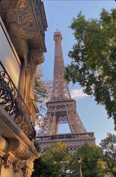 the eiffel tower in paris, france is seen from behind some buildings and trees