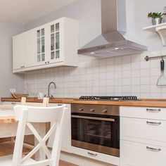 a kitchen with an oven, stove and dining table in the center is white cupboards