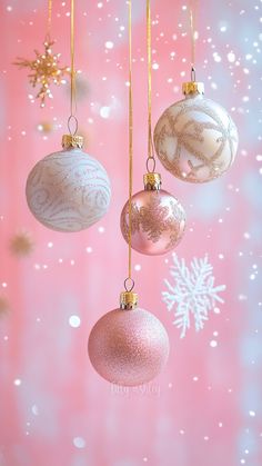 three christmas ornaments hanging from strings against a pink background with snowflakes and stars