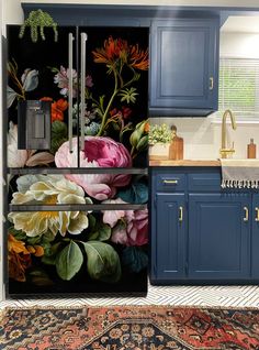 a kitchen with blue cabinets and an area rug on the floor that has flowers painted on it