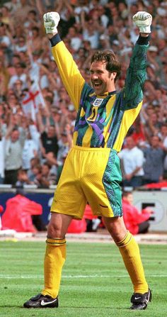 a soccer player holding his arms up in the air while standing on top of a field