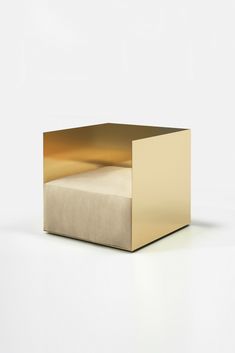 a gold colored box sitting on top of a white floor next to a pillow and blanket