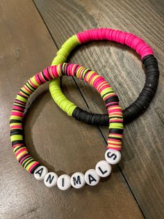 two bracelets with name beads on them sitting on top of a wooden table next to each other