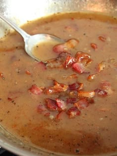 a spoon in a bowl filled with soup and bacon on the side, ready to be eaten