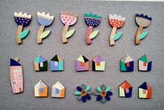 colorful wooden flowers and houses are arranged on a gray surface with grey felt backings