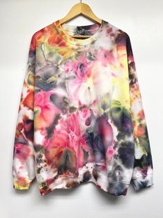 a multicolored sweatshirt hanging on a hanger with flowers all over the top