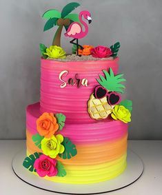 a colorful cake decorated with flowers and a flamingo sitting on top of the cake