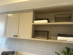 a kitchen with white cabinets and shelves filled with towels