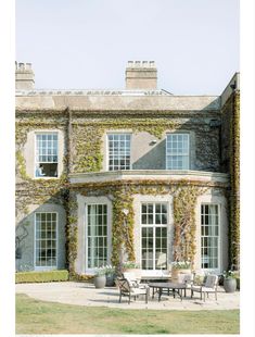 an old house with ivy growing on it's walls and patio furniture in the foreground