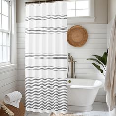 a white and black striped shower curtain next to a bathtub in a bathroom with a rug on the floor