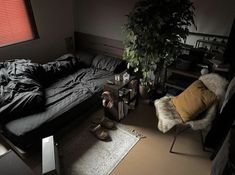 a bed room with a neatly made bed next to a window and a plant in the corner