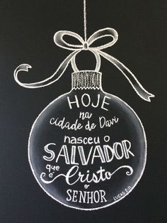 a chalkboard ornament hanging from a string on a black background with words written in spanish