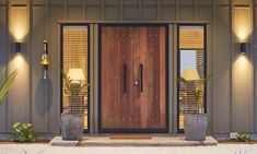 a front door with two planters on each side and one light on the other