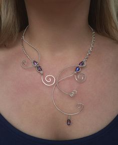 Handcrafted Silver Wire Wrapped Open Collar Necklace, a stunning piece inspired by medieval and Renaissance elegance. Adorned with iridescent purple, blue, and pink shift glass teardrop beads, this elvish torc necklace is perfect for special occasions, cosplay events, or adding a touch of fantasy to your everyday look. The intricate wire wrapping and open collar design ensure a comfortable fit while showcasing its unique craftsmanship. Elevate your style with this exquisite, one-of-a-kind necklace To keep your silver-plated jewelry looking its best, we recommend avoiding contact with harsh chemicals, perfumes, and excessive moisture. Gently wipe it clean with a soft cloth after wearing to preserve its shine and quality. **I use a combination of high quality glass beads, acrylic beads and n Open Collar Necklace, Silver Elven Jewelry For Festivals, Silver Elven Style Jewelry For Festivals, Medieval Style Metal Necklaces For Larp, Handmade Adjustable Medieval Necklaces, Adjustable Handmade Medieval Necklaces, Handmade Fantasy Necklaces For Larp, Torc Necklace, Cosplay Jewelry