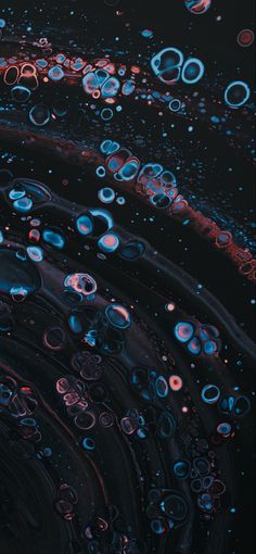 an abstract photo with blue and red circles on black background, as well as water droplets