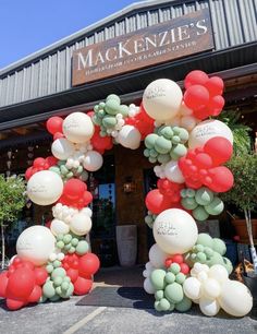 an arch made out of balloons with names on it in front of a storefront