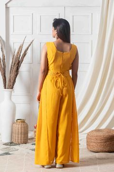 Dipped in class and elegance, this indo-western jumpsuit has a modern take with it's extended pleats running from the sleeves to the ankle. Featuring mirror work detailing on the front bodice with a belt running across, this jumpsuit has an alluring fit and silhouette to help you look striking on a day or evening event!Style Indo-western jumpsuit Extended pleats style Cut sleeves Mustard color Ankle-length Flared style Mirror-work detailing Georgette fabric Specifications Model height - 5'7" Mod Festive Maxi Length Jumpsuits And Rompers, Fitted Ankle-length Summer Sets, Western Jumpsuit, Mustard Color, Sunshine Yellow, Indo Western, Georgette Fabric, Mirror Work, Event Styling