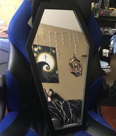 a mirror sitting on top of a blue chair next to a wall with pictures hanging from it