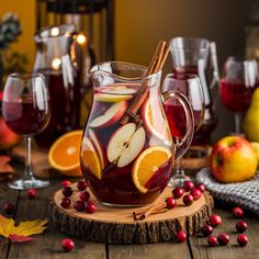 a pitcher filled with liquid surrounded by sliced oranges and cranberries on a wooden table