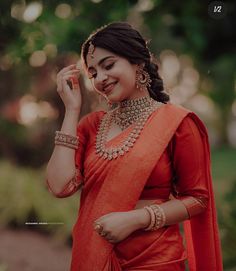 a woman in an orange sari is smiling and holding her hand up to her ear