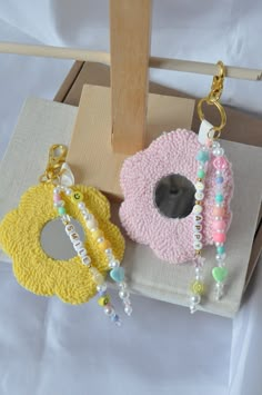 two necklaces are sitting on a piece of cloth next to a wooden stand with a mirror