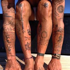 two people with tattoos on their legs and feet standing next to each other in shorts