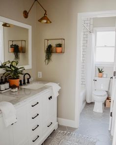 a bathroom with two sinks, mirrors and plants on the wall above the vanity area