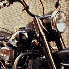 two motorcycles parked next to each other in front of a brick wall