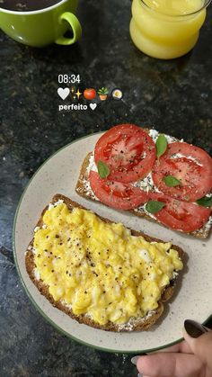 someone is holding a plate with two pieces of bread and some tomatoes on it next to a cup of coffee