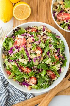 two white bowls filled with salad next to lemons