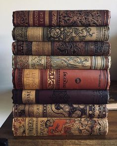 a stack of old books sitting on top of a wooden table next to a phone