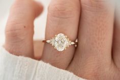 a woman's hand with a diamond ring on top of her finger and the other hand holding an engagement ring