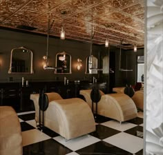 the interior of a hair salon with black and white checkered flooring, chandeliers and mirrors