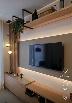 a flat screen tv mounted to the side of a wall next to a wooden shelf