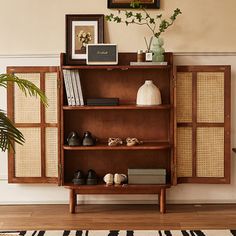 a wooden shelf with shoes on top of it next to a potted plant and framed pictures