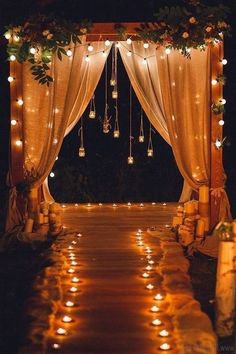 an outdoor wedding ceremony with candles lit up on the aisle and lights hanging from the ceiling