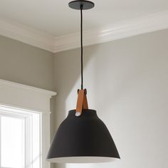 a black lamp hanging from a ceiling in a room with white walls and windows behind it