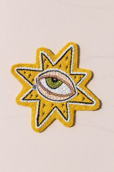 an embroidered patch with the eye and stars in yellow, white and green on it