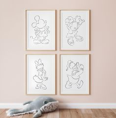 three framed cartoon drawings hang on the wall next to a stuffed animal in front of them