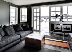 a living room filled with furniture next to windows and a camera on a tripod