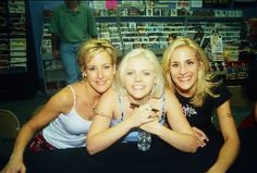 three women are posing for the camera in front of a book store with their arms around each other