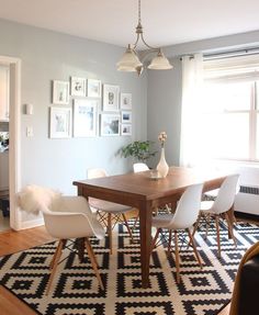 a dining room table with chairs and pictures on the wall above it, along with an area rug