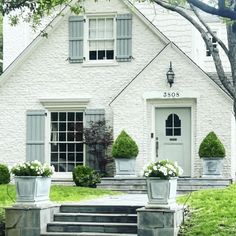 a white house with two planters on the steps