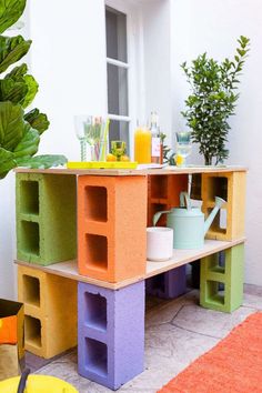 an outdoor table made out of cinder blocks with plants in the corner and cups on top