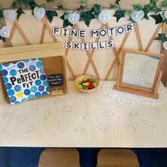 a table topped with books and toys on top of a white table covered in green leaves