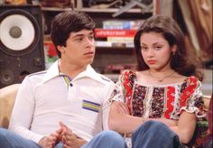 the young man and woman are sitting together in front of an old fashioned speaker system