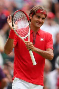 a man holding a tennis racquet on top of a tennis court with people in the background